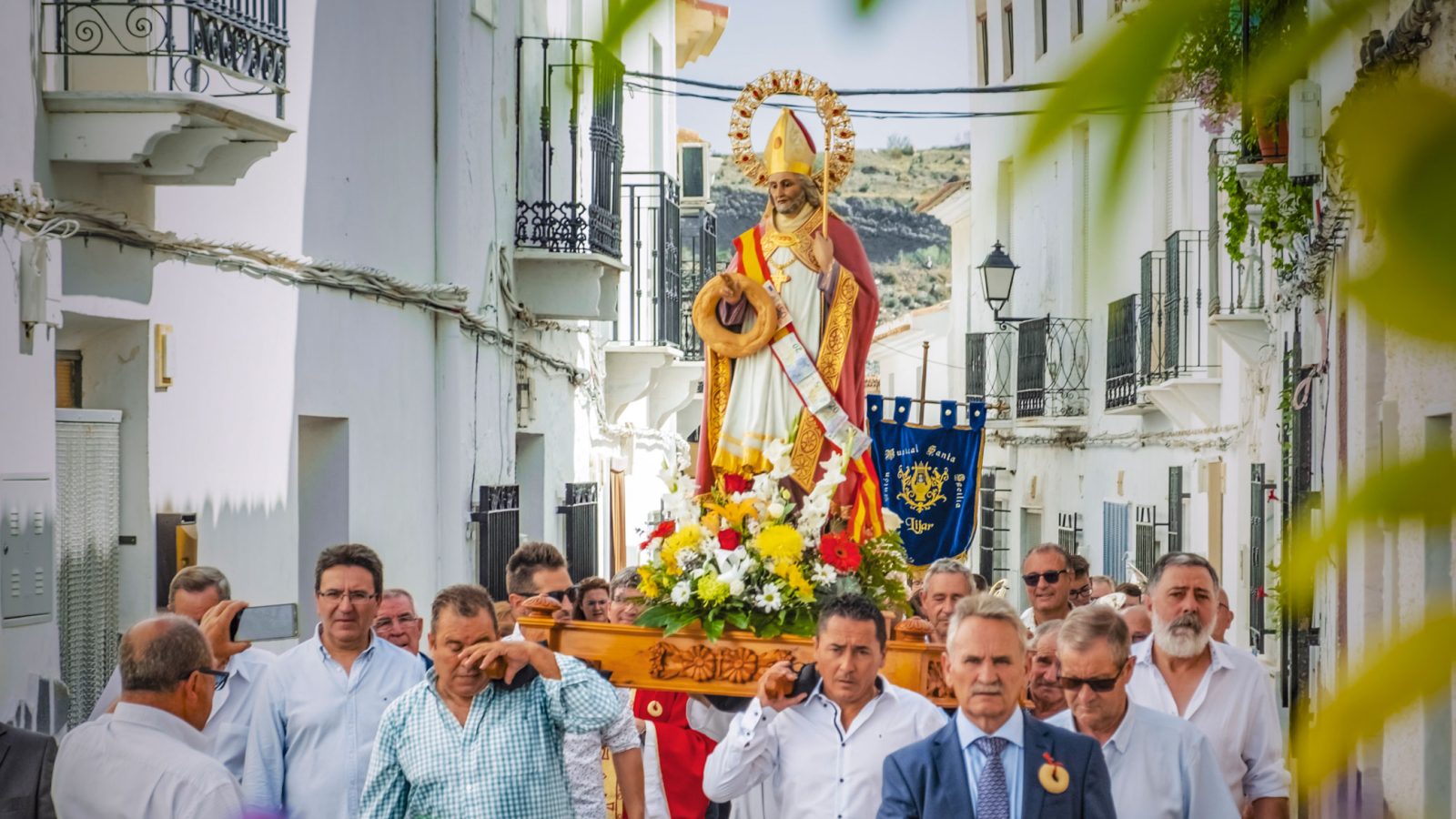 La imagen de San Blas, a hombros en procesión por una calle blanca de Líjar