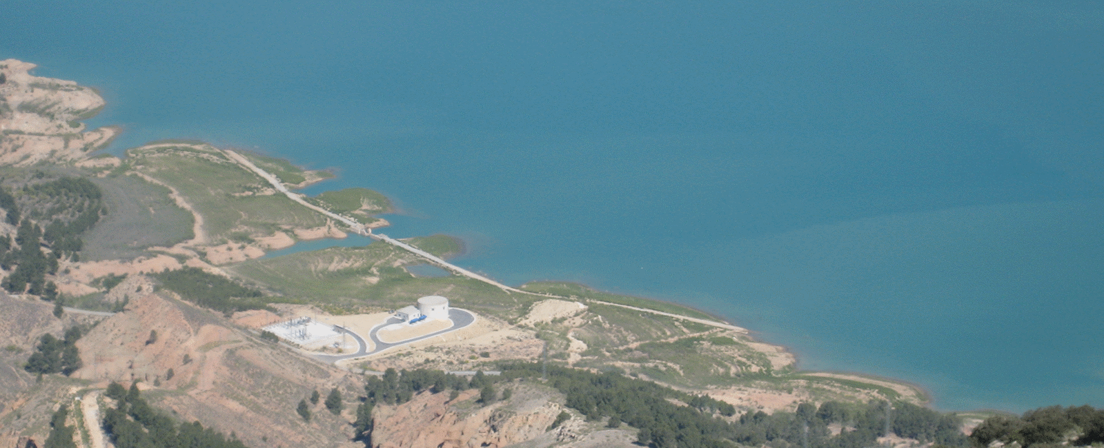 Vista aérea de un embalse con unas instalaciones hidráulicas en la orilla