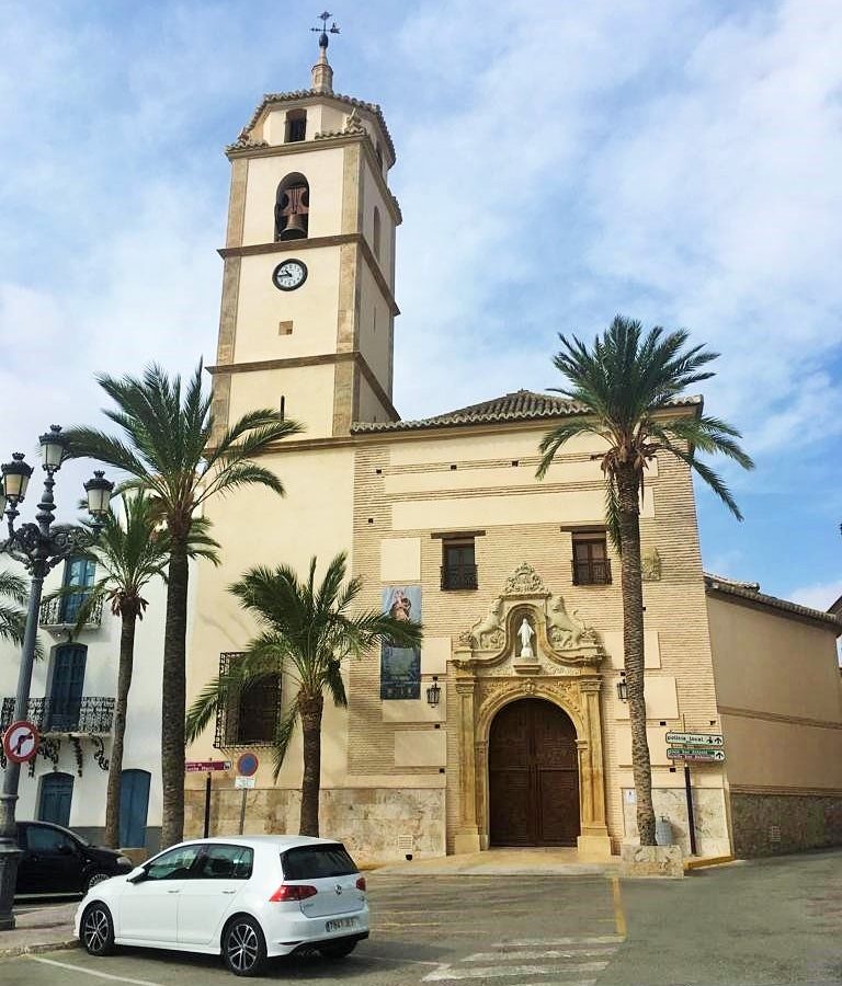 Fachada y torre de la iglesia de Santa María de Albox, entre palmeras