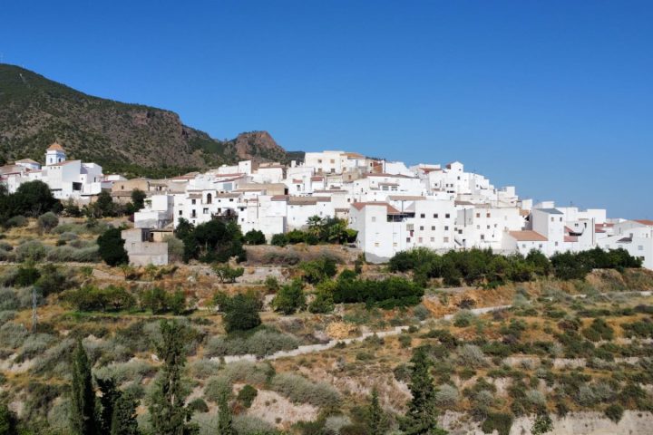 Vista aérea de Urrácal: casas blancas al pie de la sierra, rodeadas de bancales