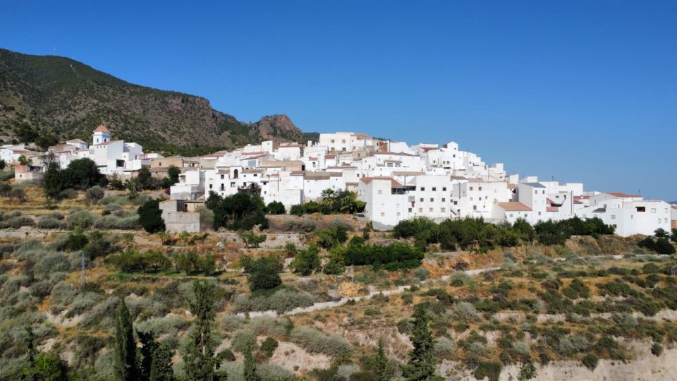Vista aérea de Urrácal: casas blancas al pie de la sierra, rodeadas de bancales