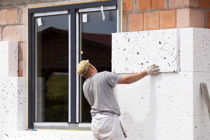 Un trabajador coloca paneles de aislamiento térmico en la fachada de una vivienda