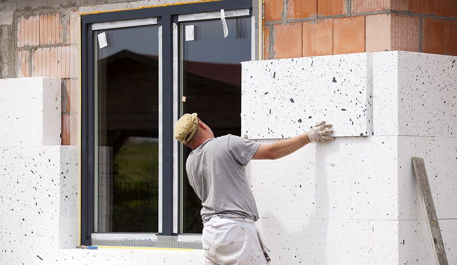 Un trabajador coloca paneles de aislamiento térmico en la fachada de una vivienda