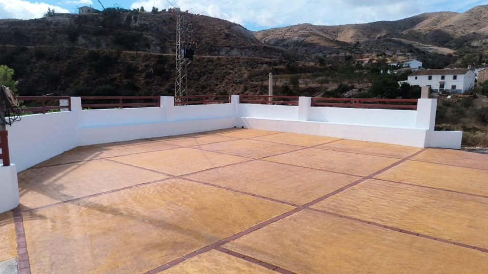 Plaza de Los Pardos, en Cantoria, con suelo de hormigón impreso, muros blancos y barandilla roja