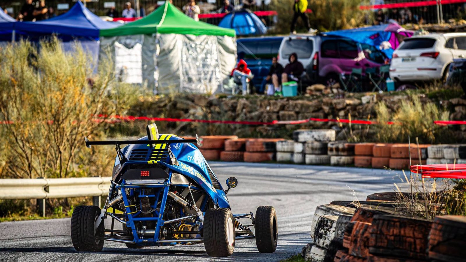 Car cross azul en una curva de la Subida del Mármol, con público al fondo