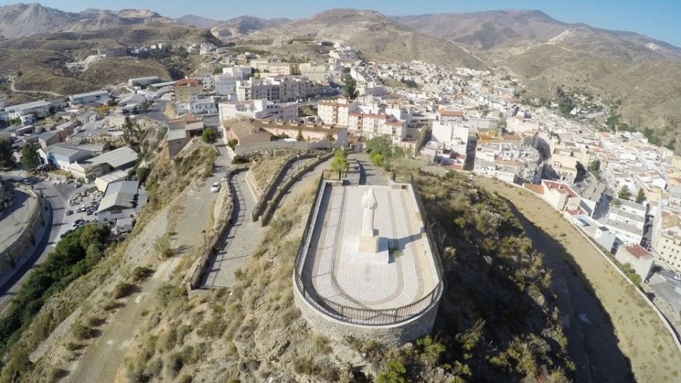 Vista aérea de Macael, con un monumento en primer plano y la sierra al fondo