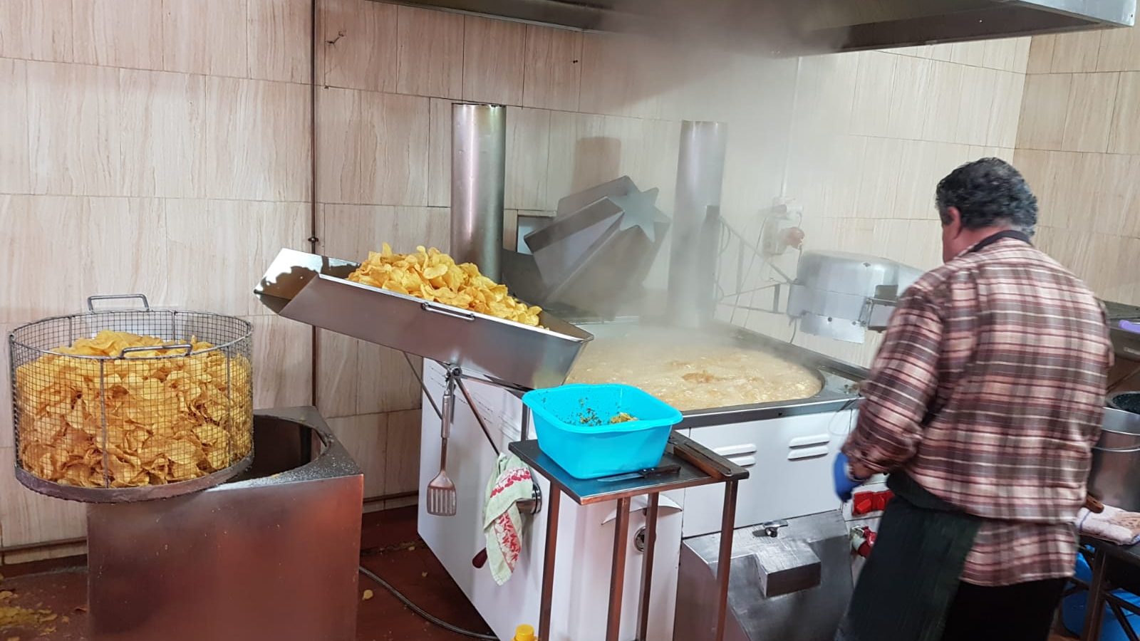 Un trabajador fríe patatas en la Churrería Agapito de Tíjola, junto a una cesta llena